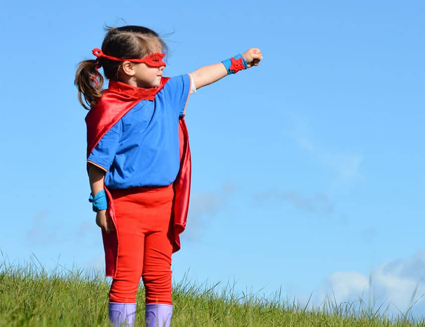 Child dressed as superhero in field